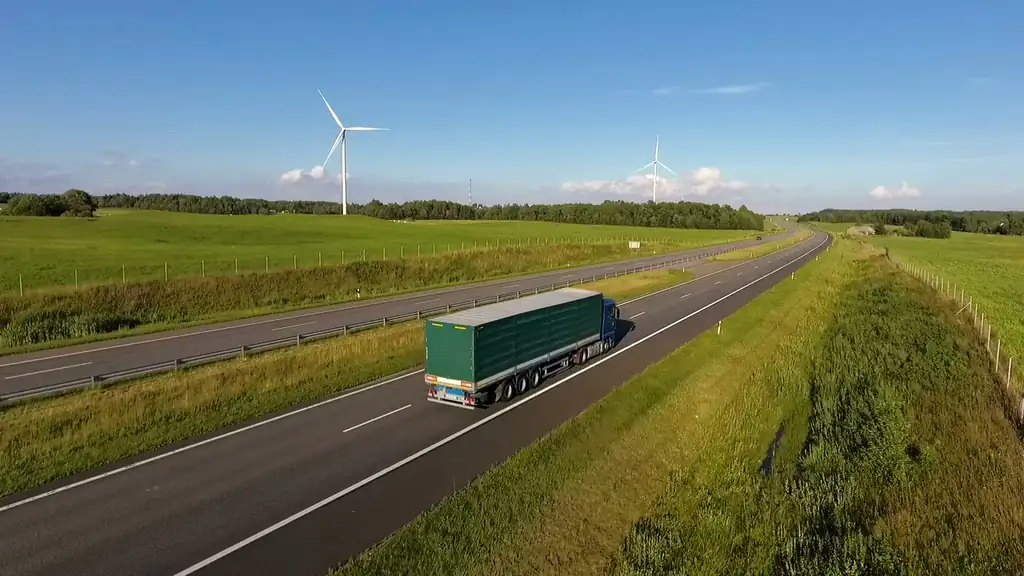 HGV on a green motorway with a wind turbine in the distance