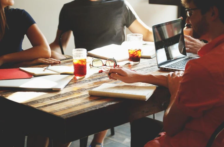 Team meeting around a table with laptops and notes